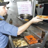 The Chief Cook of HMCS Whitehorse serves perogies and sausage to the crew. Photo by Lt (N) Paul Pendergast, Canadian Joint Operations Command Public Affairs Officer