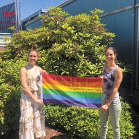 Amy Gordichuk and Alli Jones, members on the Positive Space Working Group, hold up the new Pride flag that is now on a flag pole at CFB Esquimalt.