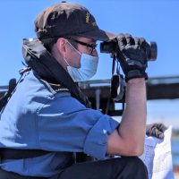 Sailor Second Class Nick Reicker uses binoculars to scout for and identify nautical flags during a recent training exercise off the jetty of HMCS Malahat.