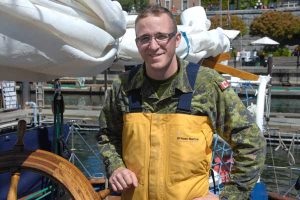 Cpl Dominic Pare pauses for a photo at the helm of HMCS Oriole