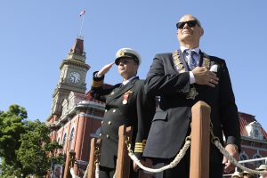 Victoria Mayor, Mr Dean Fortin (Right) and CFB Esquimalt Base Commander, Capt(N) Luc Cassivi (Left) salute the parade from the dais at Centennial Square, Victoria, BC while the participants march past during the 116th Annual Victoria Day Parade.