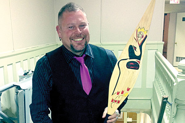 Besides writing, Ed Brown has also taken up carving to honour his First Nations heritage. He stands proudly holding one of his own designs.