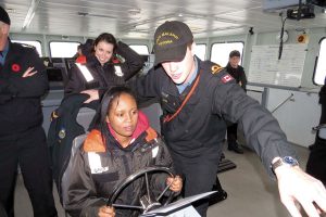 A/SLt Matthew Heim of HMCS Malahat shows Sara Geday how to “drive” a 33-metre Orca-class vessel. 