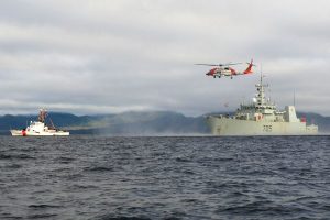 HMCS Whitehorse conducts a hoist exercise with a United States Coast Guard (USCG) SH60 Jayhawk helicopter near Mary Island, Alaska, on Feb. 18, while the USCG Ship Liberty sailed in formation. 