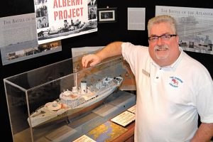 Lewis Bartholomew, Founder and Director of HMCS Alberni Museum and Alberni Project stands proudly next to a model of HMCS Alberni.