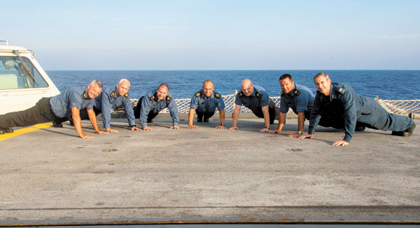 HMCS Charlottetown’s Chiefs (from left to right) CPO2 Kent Ellerbeck, CPO2 Robert Embree, CPO2 Dave Skinner, ship’s Coxswain CPO1 Anthony Greig Bishop, CPO2 Mathew Boniface, CPO2 Kevin Reid and MWO Mike Windsor participate in the 22 Push-up Challenge on the flight deck during OP Reassurance in the Mediterranean Sea. Photo by Cpl Blaine Sewell, Formation Imagery Services
