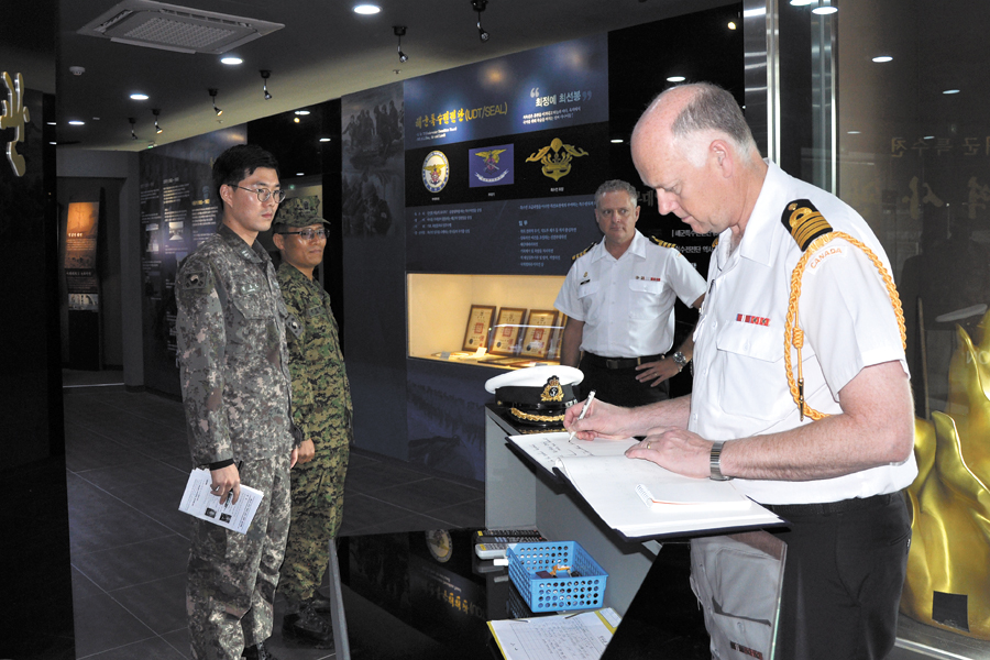 Capt(N) James Cotter, Canadian Defence Attaché, signs the guestbook at the museum.