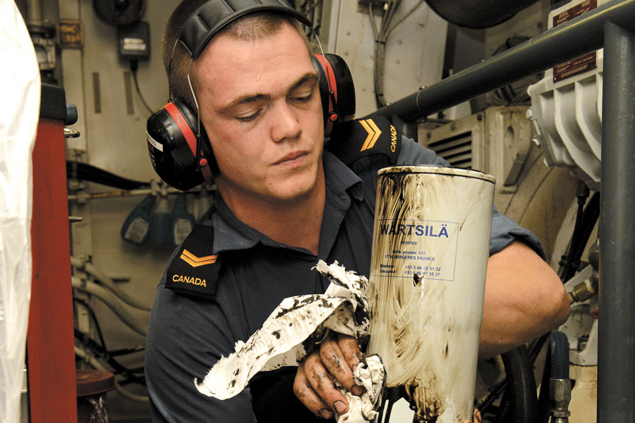 A Marine Engineering Systems Operator cleans an oil filter from a diesel alternator.