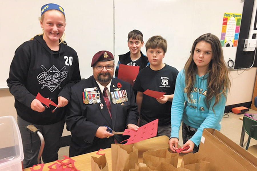 Students from Rockheights Middle School prepare poppies for a No Stone Left Alone ceremony with Sgt (Ret'd) Jim MacMillan-Murphy, 1st Vice President, Royal Canadian Legion Branch 172. Photo credit: Rock Heights Middle School