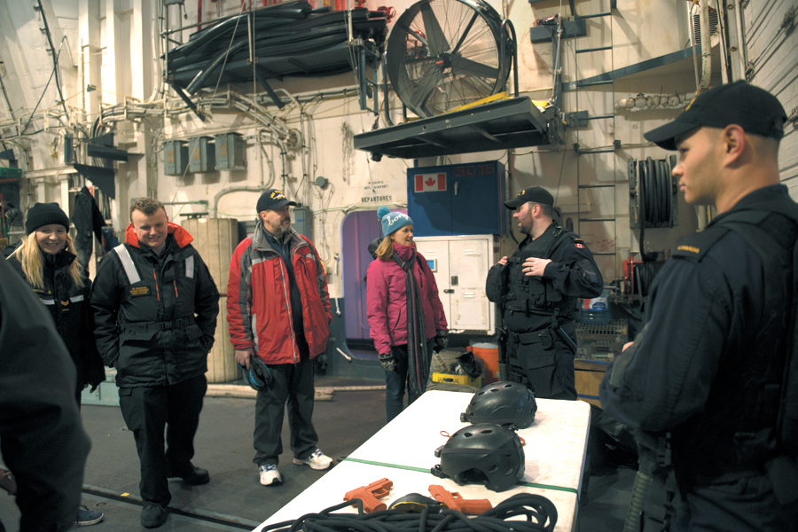 LS Gray (left) and LS Yance (right) show off naval boarding party equipment to visitors in the hangar.