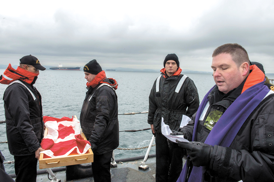 Major Mike Gibbons (right), Senior Fleet Chaplain, says a prayer as he conducts a burial at sea ceremony prior to the ashes being committed to the sea. Photos by MCpl Brent Kenny, MARPAC Imaging Services