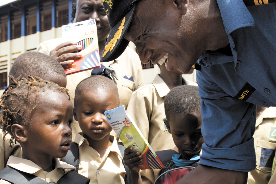 Lieutenant-Commander Paul Smith, Commanding Officer of HMCS Summerside, hands out donations to students from St. Edwards Primary School in Freetown, Sierra Leone. Photo by MCpl Pat Blanchard, Canadian Forces Combat Camera, DND