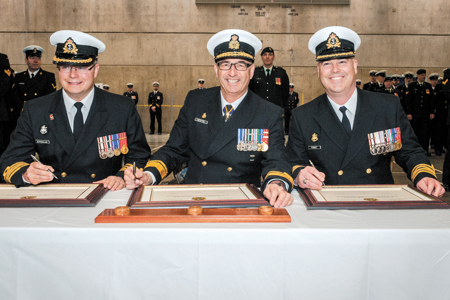 From left: Outgoing CFB Halifax Base Commander Capt(N) Chris Sutherland, RAdm John Newton, and incoming Base Commander Capt(N) Paul Forget sign documents at the Change of Command ceremony held at HMCS Scotian on March 31.