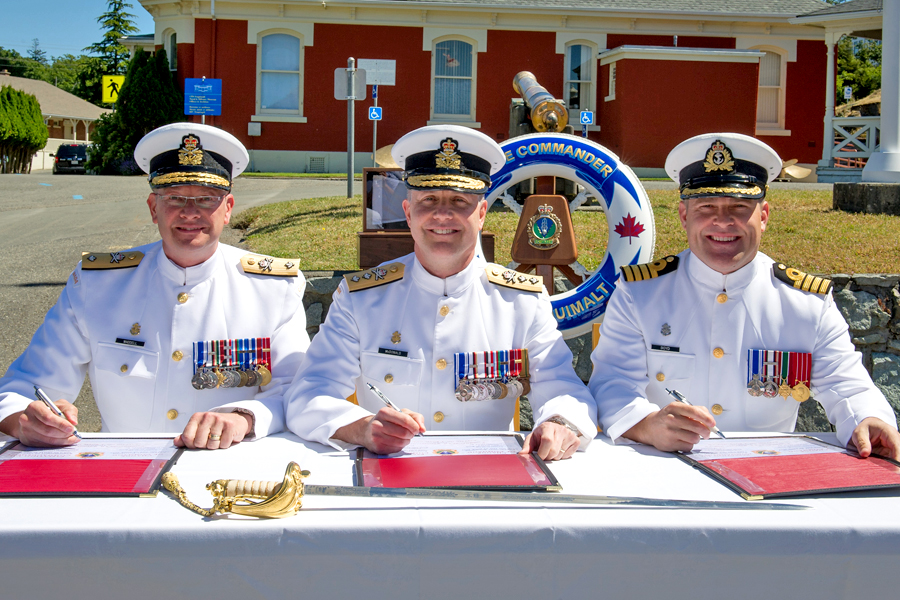 (Centre) Rear-Admiral Art McDonald, Commander Maritime Forces Pacific; former Base Commander Commodore Steve Waddell (left); and incoming Base Commander Captain (Navy) Jason Boyd (right), sign off on papers officially appointing Capt(N) Boyd to his new post during a Change of Command Ceremony at Museum Square, June 22.