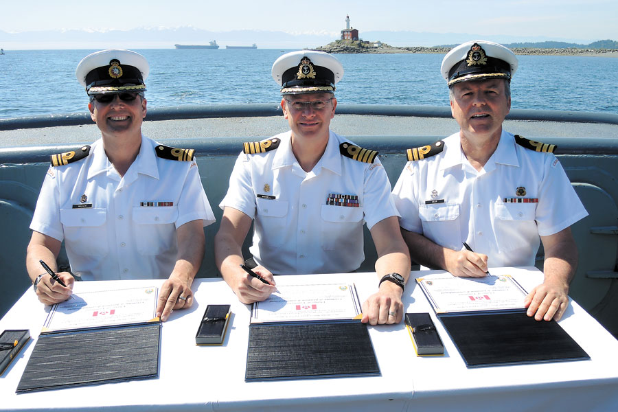 Base Commander Capt(N) Steve Waddell, center, signs the change of command certificates that officialises passing command of Port Operations and Emergency Services from outgoing Cdr Andrew Muir to incoming Cdr Greg Walker. Photos by Peter Mallett, Lookout Newspaper