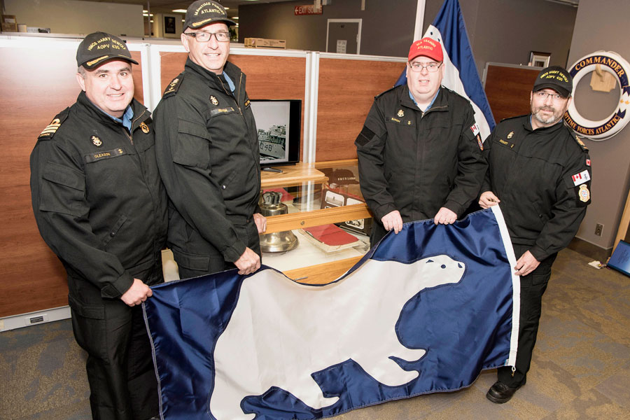 In front of the Arctic display outside the Commander of Maritime Forces Atlantic’s (MARLANT) office, Cdr Corey Gleason, Commanding Officer HMCS Harry DeWolf; RAdm John Newton, MARLANT; CPO2 Rick Bungay, Sea Training Atlantic; and CPO1 Gerry Doucet, Coxswain HMCS Harry DeWolf, display the Polar Flag. Photo by Mona Ghiz, MARLANT PA