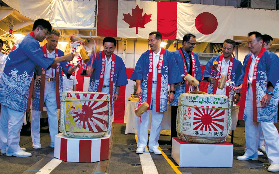 Rear-Admiral G. Couturier, Deputy Commander Royal Canadian Navy, watches Commander S. Belair, Commanding Officer, HMCS Ottawa, break open the sake casks at a reception onboard Japanese Maritime Self-Defense Force Ship Umigiri on July 11 during a port visit to Tokyo, Japan, on Poseidon Cutlass 17. Photo: Royal Canadian Navy Public Affairs