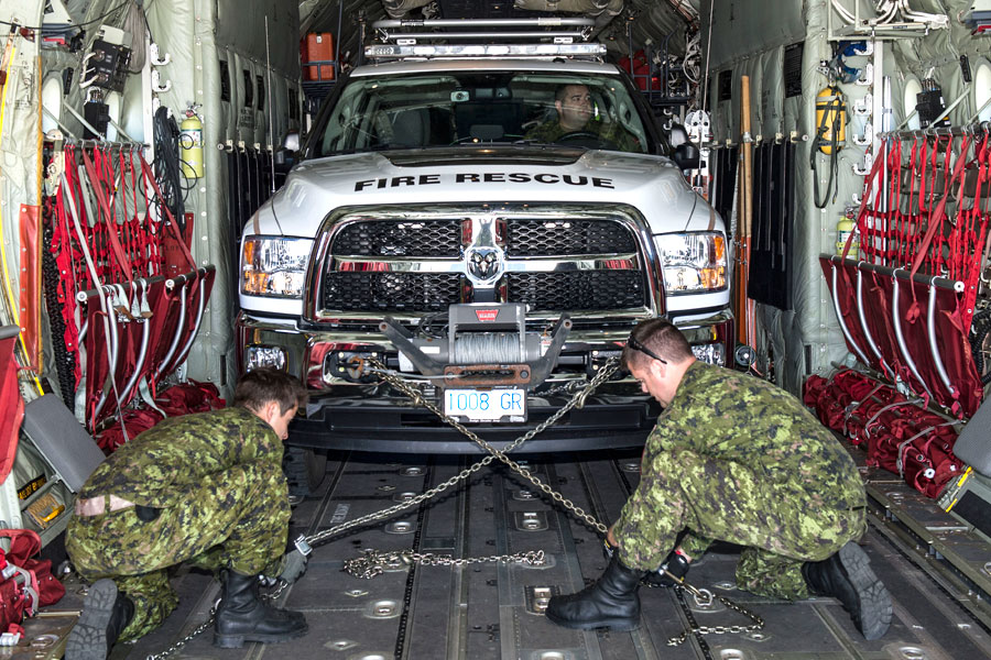 Members of 19 Wing Comox secure a fire rescue truck after loading it onto a C-130 Hercules aircraft at CFB Comox in support of Operation Lentus, which is providing support in fighting the wildfires in B.C.’s interior. Photo by Cpl Jeffrey Clement, 19 Wing Imaging