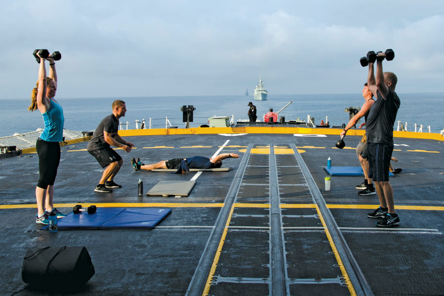 LCdr Meryl Sponder (left) completes an overhead press on the flight deck of HMCS Ottawa during an early morning fitness window. LCdr Sponder was the winner of a Biggest Loser Challenge, losing the most body weight of any of the competitors. Photo by Alyssa Jesson, PSP