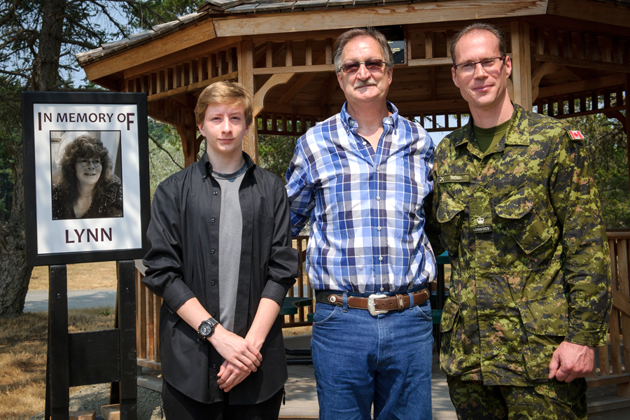 Lynn Gardner’s husband, Jamie Allin (centre) and their son, Gregory, join former Rocky Point Commanding Officer Major Jean-Luc Rioux during a gazebo dedication ceremony for Gardner on Aug. 3. Photo by Cpl Stuart MacNeil, MARPAC Imaging Services
