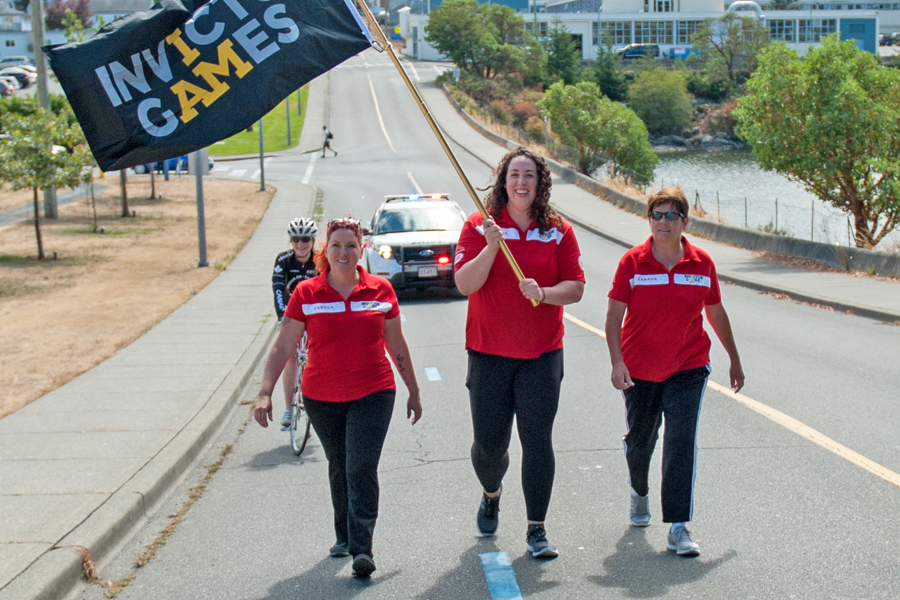 Lt(N) Krista Seguin waves the Invictus Games flag at CFB Esquimalt Aug. 16. Photo by LS David Gariepy, MARPAC Imaging