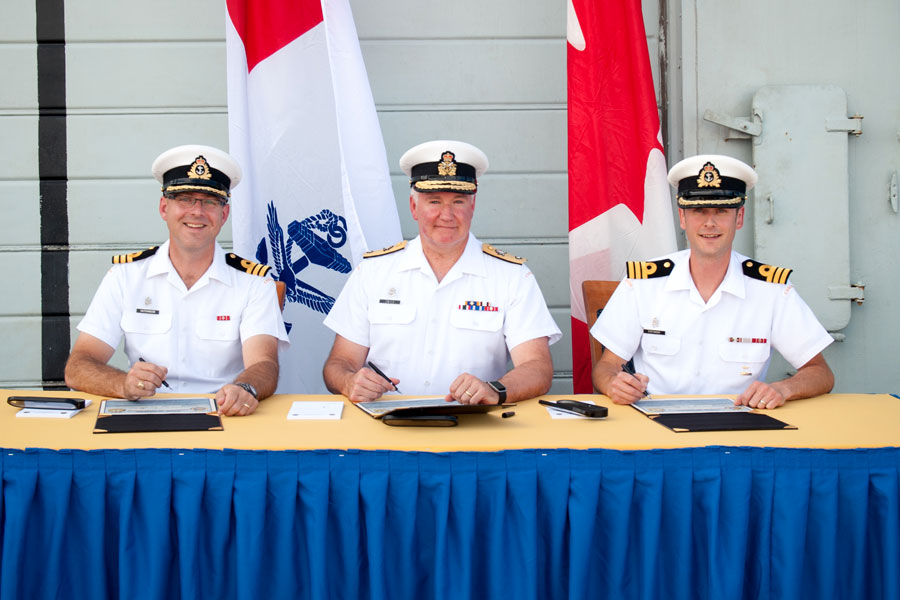 Reviewing Officer, Commodore Jeff Zwick (centre), signs the certificate officiating the command change between Outgoing Commanding Officer of HMCS Winnipeg, Commander Jon Hutchinson (left), and the Incoming Commanding Officer, Commander Michael Stefanson (right), during the Change of Command Ceremony at A Jetty, Aug. 23. Photo by LS David Gariepy