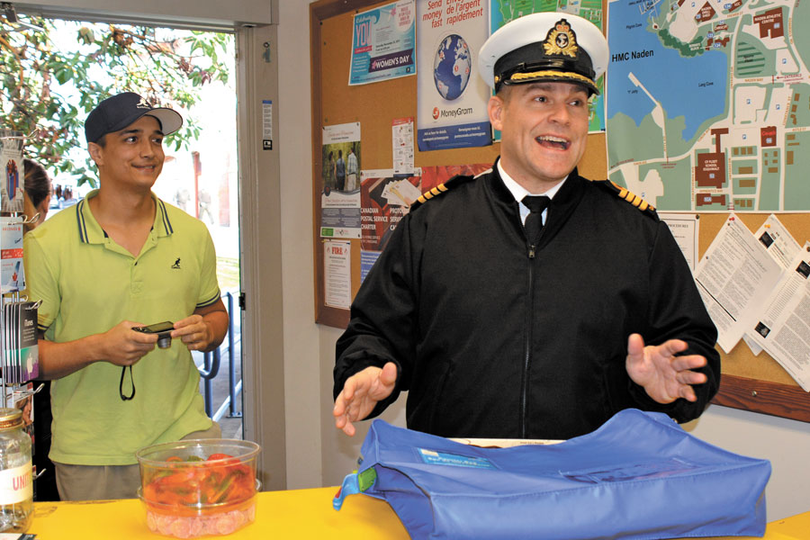 Corporal Christopher Imamshah, from Personnel Coordination Centre, looks on as Base Commander Capt(N) Jason Boyd handles mail and hands out treats. Cpl Imamshah single-handedly secured the Base Commander with a donation to the National Defence Workplace Charitable Campaign’s “You’re the Boss” auction.