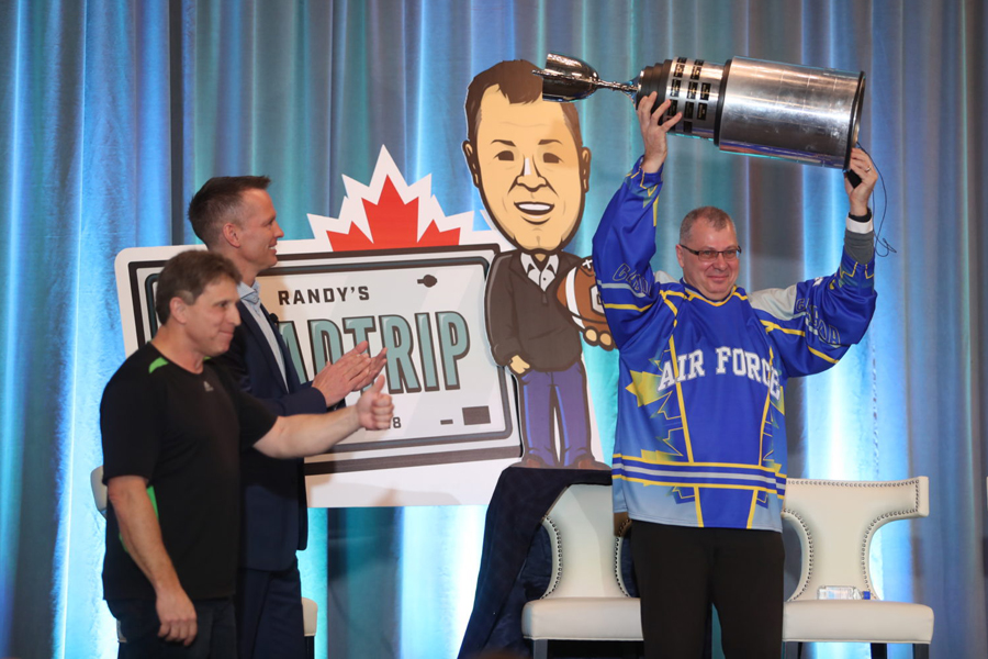 From left, Wally Buckoski of PSP Halifax and Paul Hollingsworth of TSN look on as CFL Commissioner Randy Ambrosie hoists the Mini Grey Cup during his town hall event in Halifax on February 23. Photo by Mike Dembeck, CFL.CA