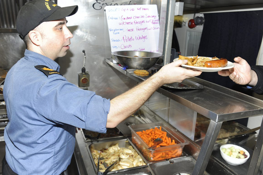 The Chief Cook of HMCS Whitehorse serves perogies and sausage to the crew. Photo by Lt (N) Paul Pendergast, Canadian Joint Operations Command Public Affairs Officer