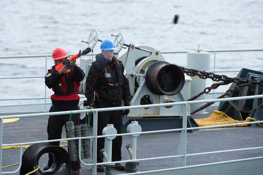 A crewmember on board HMCS Whitehorse fires a line towards HMCS Edmonton during a light line transfer while sailing in the eastern Pacific Ocean, April 26. Photo by MARPAC Imaging Services