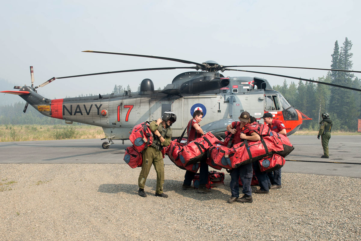 Members of the British Columbia Forest Service pick up their bags after being dropped off by a Sea King in support of OP LENTUS Aug. 21. Photo by Cpl Jeffrey Clement