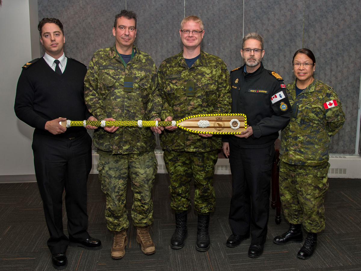 HMCS Yellowknife crewmember, Leading Seaman Daniel Cramer (left) presents a decorative paddle to (left to right) mess committee presidents Major Jason Blake and Warrant Officer Daryll Wilts, Joint Task Force (North) Deputy Commander, Captain (Navy) Sylvain Belair, and Formation Chief Warrant Officer Sherri Forward during the ship’s namesake city visit on Sept 12. Photo by MCpl Charles A. Stephen, Imagery Technician