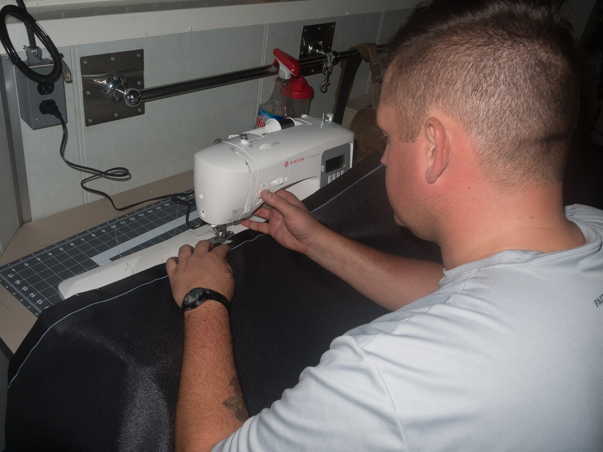 A Boatswain in works to sew some privacy curtains.