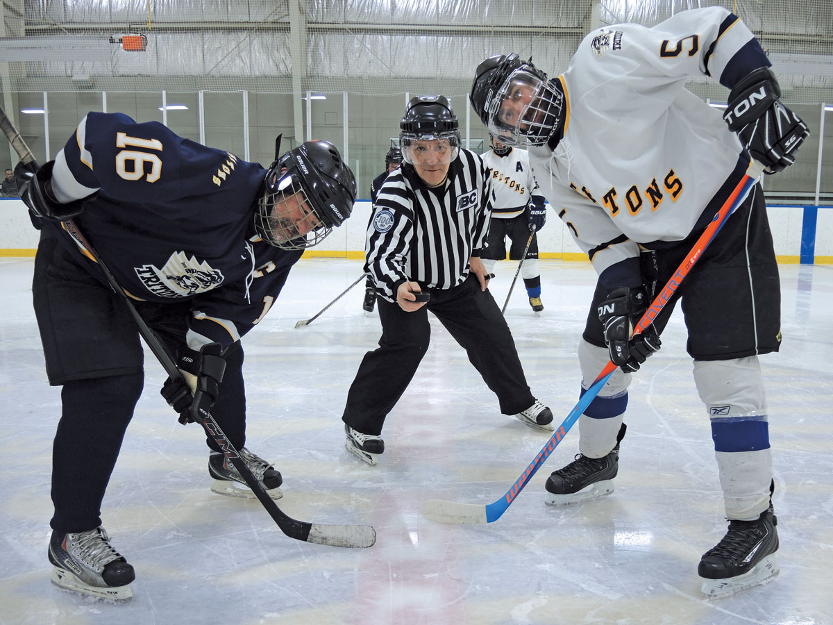 On the left, PO1 Marc Buzzi of Team Howlett and CPO2 Josh Barnes get set for the opening puck drop by referee CPO2 Yves Ouellet. Photo by Peter Mallett, Lookout