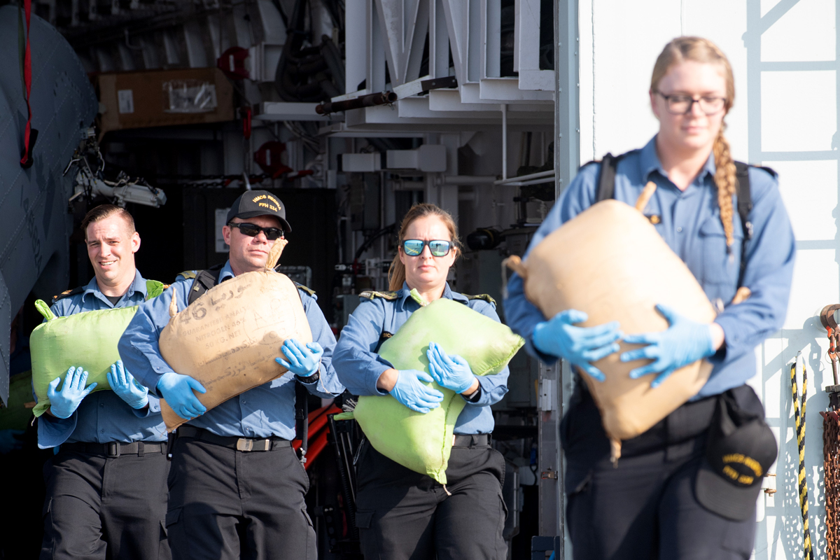 From left: Master Seaman Mark Sebulsky, Master Corporal Derek Scott, Corporal Chantale Robichaud and Leading Seaman Jessica Armstrong transport the first load of seized hashish to the ship’s flight deck. Photo by MCpl PJ Letourneau, CF Combat Camera