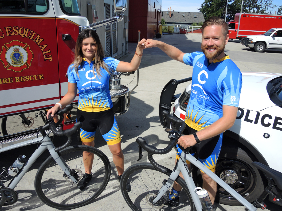 CFB Esquimalt Fire and Rescue Services Alexandria Marshall (left) and Corporal Michael Smith of Military Police Unit Esquimalt bump fists in front of emergency services vehicles. The duo will participate in the upcoming Tour de Rock fundraiser to benefit pediatric cancer, Sept. 21 to Oct. 4.