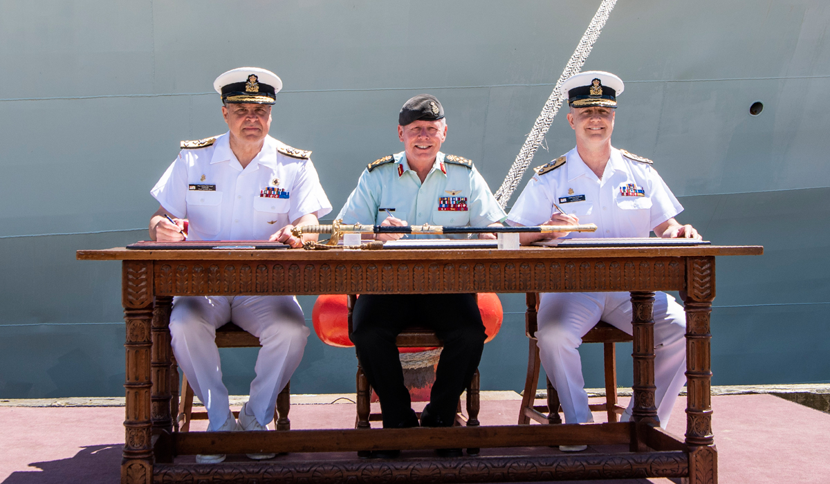 From the left: Vice-Admiral Ron Lloyd, General Jonathan Vance, and VAdm Art McDonald sign the change of command certificates, officially marking the relinquishing of command from VAdm Lloyd to VAdm McDonald. Photo by Mona Ghitz