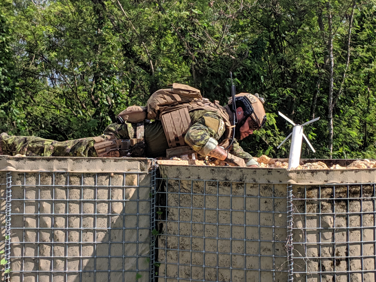 A clearance diver investigates a dud rocket in a hesco barrier of a forward operating base.