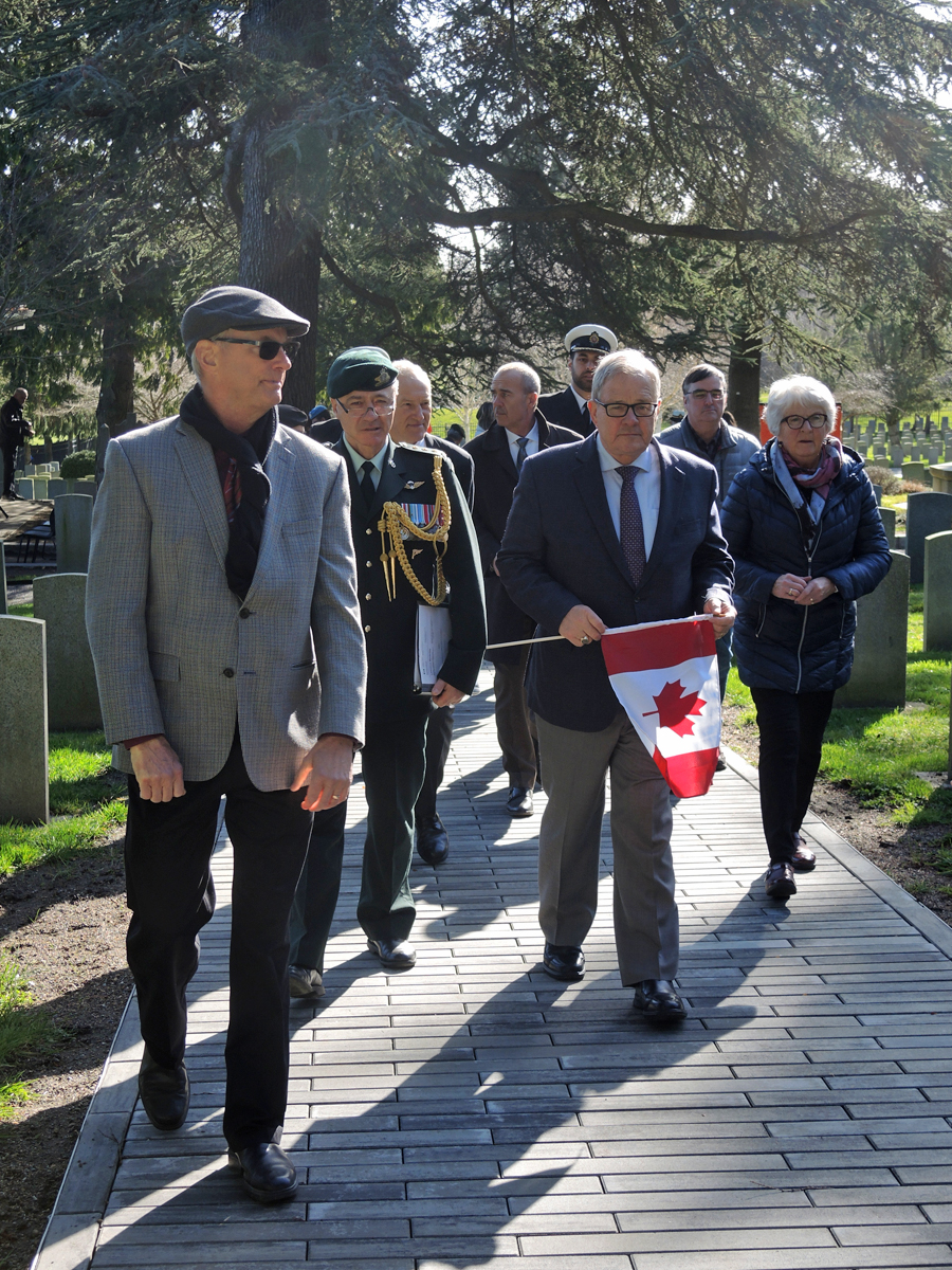 Minister of Veterans Affairs Lawrence MacAulay carries a Canadian flag to lay at a gravesite in Veteran’s Cemetery. Photo by Peter Mallett, Lookout