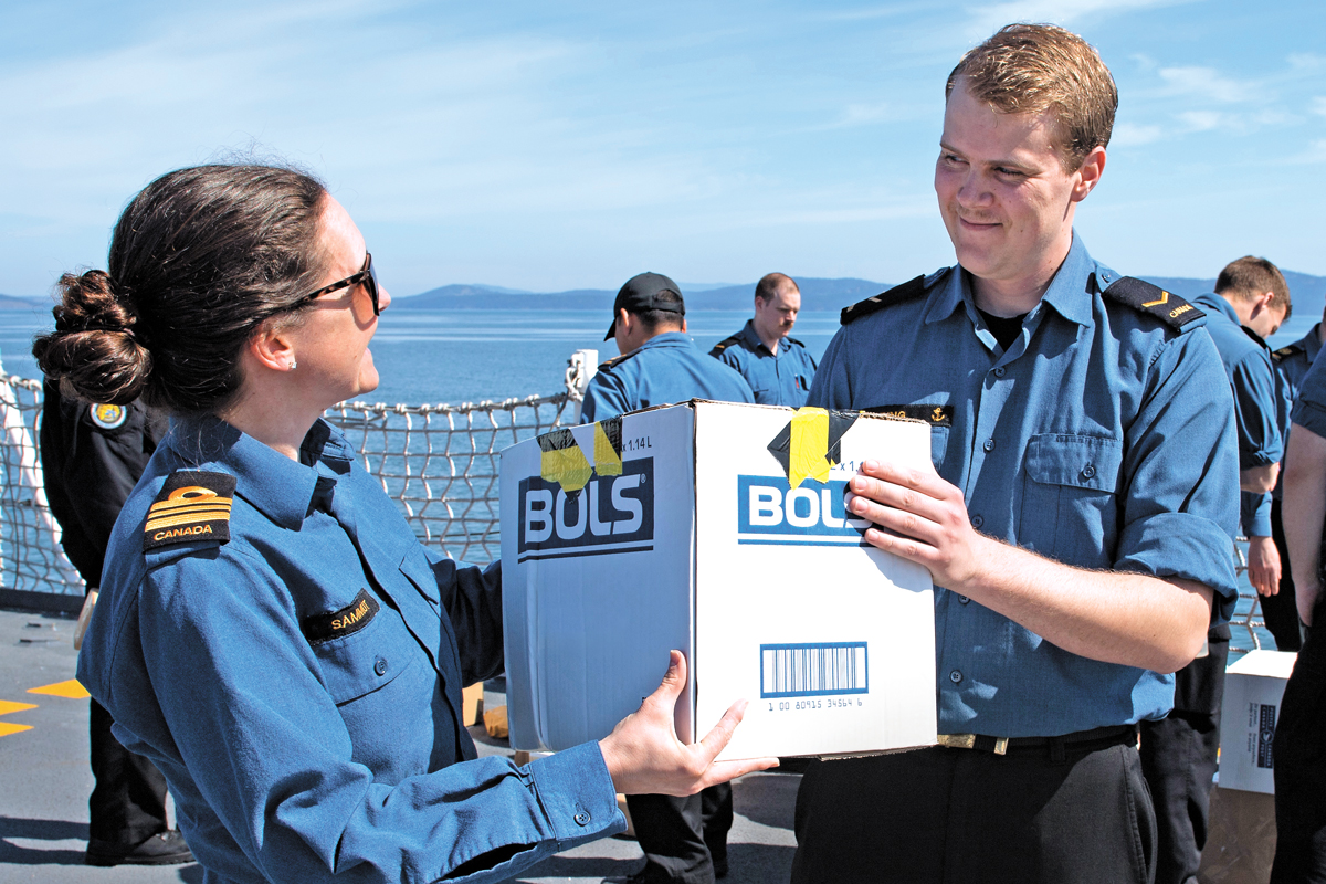 LCdr Lorraine Sammut, HMCS Calgary Executive Officer, hands a package to a crew member. Photo by Corporal Jay Naples, MARPAC Imaging Services