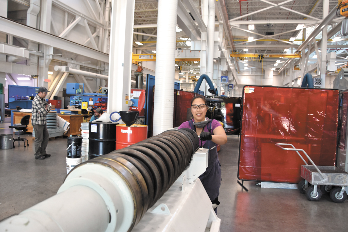 Antoniette Yap, a millwright apprentice at Fleet Maintenance Facility Cape Breton, cleans the 57mm barrel of HMCS Winnipeg’s main gun while conducting an inspection of naval ordnance.