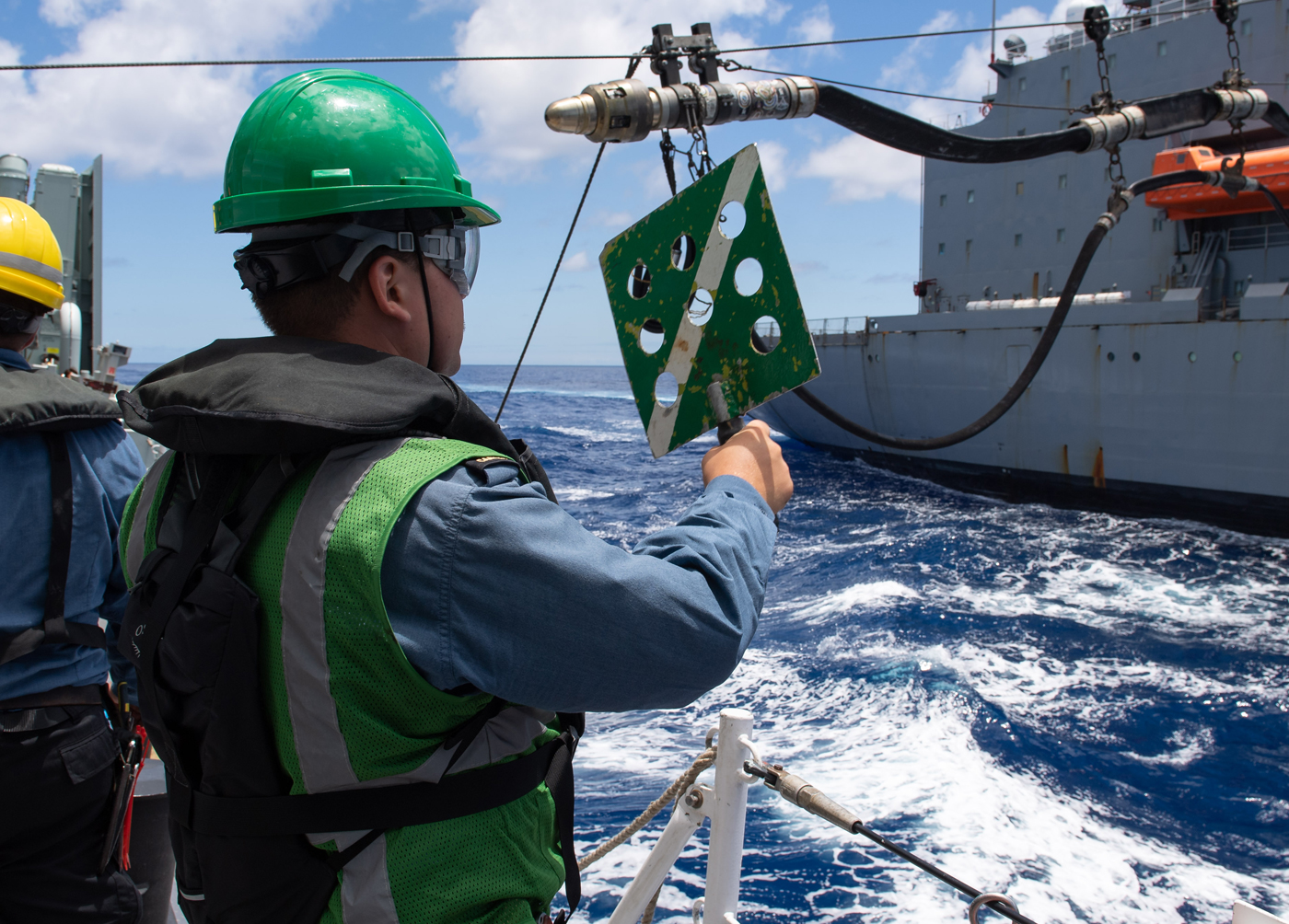 Ordinary Seaman Kilian Soch signals to USS Henry J. Kaiser during a replenishment-at-sea off the coast of the Hawaiian Islands.