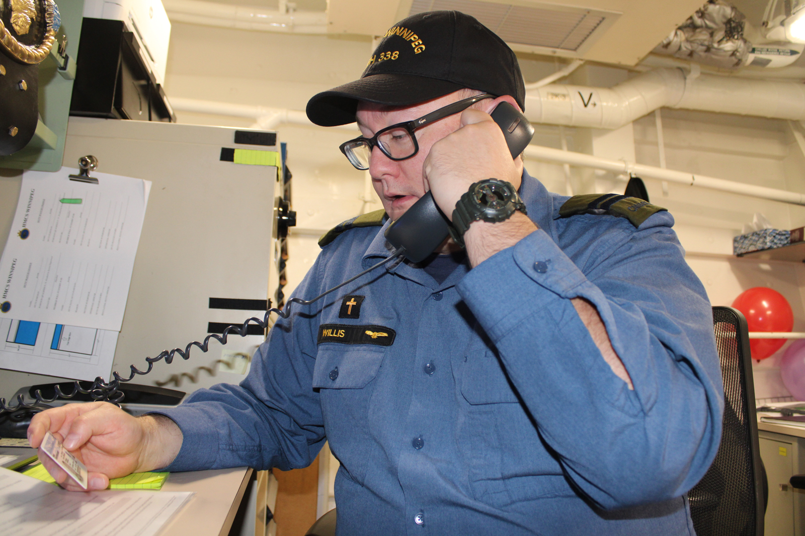 Capt Chris Willis, HMCS Winnipeg’s Padre, casts his vote in the provincial election via phone. 