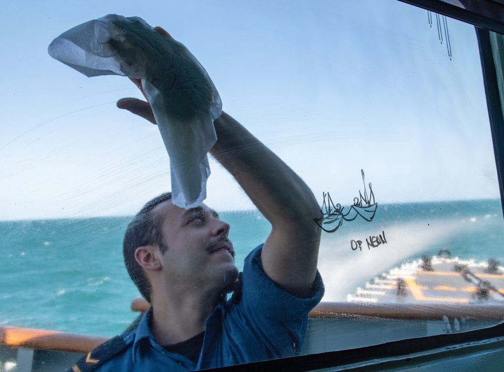 S2 Chad DeMan, a Boatswain, cleans the bridge windows during Operation Neon as the ship patrols in the East China Sea. Photo by S1 Valerie LeClair, MARPAC Imaging Services