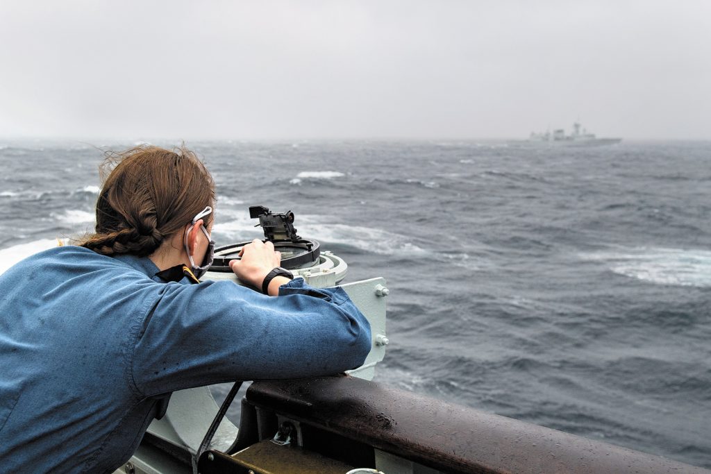 Sub-Lieutenant Kathrine Hembruff takes a bearing on HMCS Calgary from the port bridge wing of HMCS Regina during Exercise Trident Fury Dec. 3, 2020, while sailing in the West Coast Firing Area off the west coast of Vancouver Island. File Photo by Master Corporal André Maillet, MARPAC Imaging Services