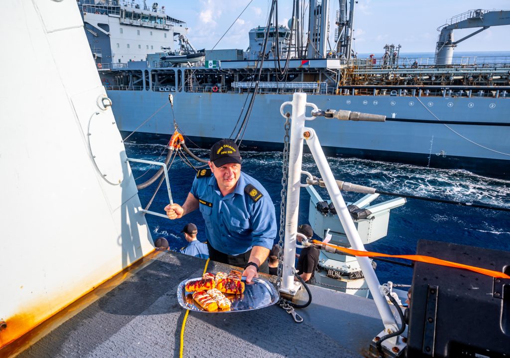 Chief Petty Officer Second Class Paul Huffman serves doughnuts – more specifically RAS doughnuts - to the officers and crew of HMCS Calgary during a replenishment-at-sea (RAS) with Her Majesty’s Australian Ship Sirius. Photo by Captain Jeff Klassen, HMCS Calgary