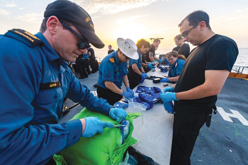 Royal Canadian Navy sailors aboard HMCS Calgary bring aboard contraband seized from smugglers during counter-smuggling operations on April 30.