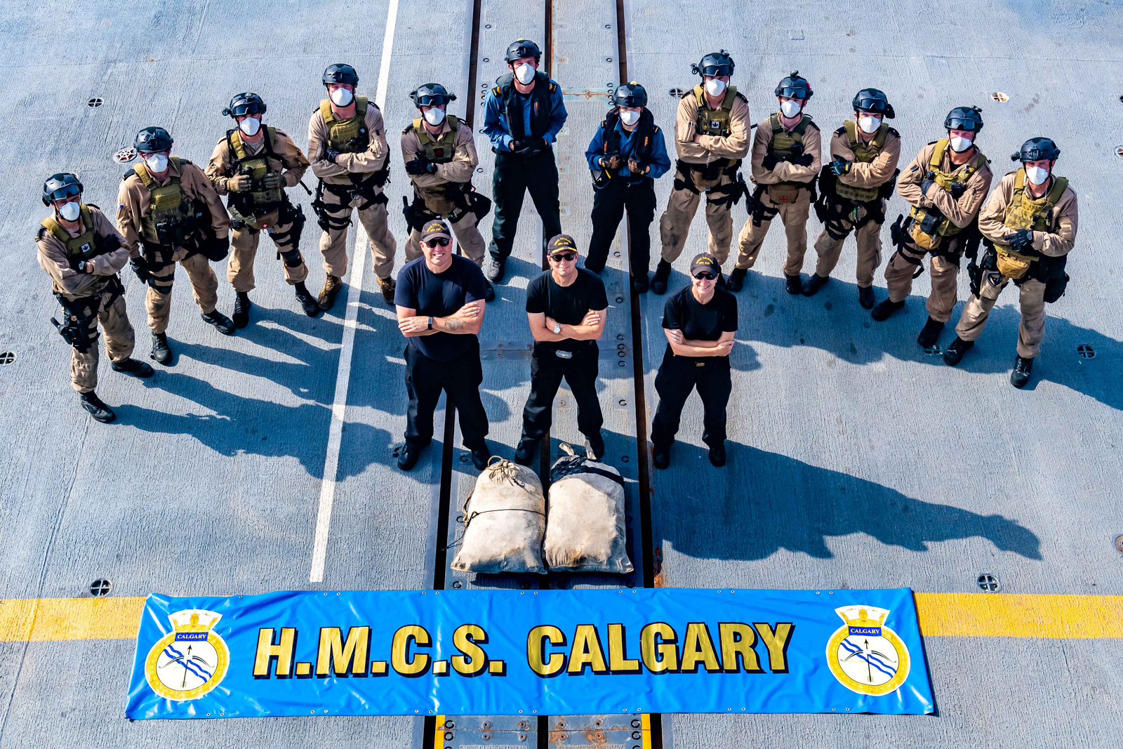 HMCS Calgary’s boarding party team and command team stand with heroin seized during counter-smuggling operations on June 6. Photo by Cpl Lynette Ai Dang, CAF Photo