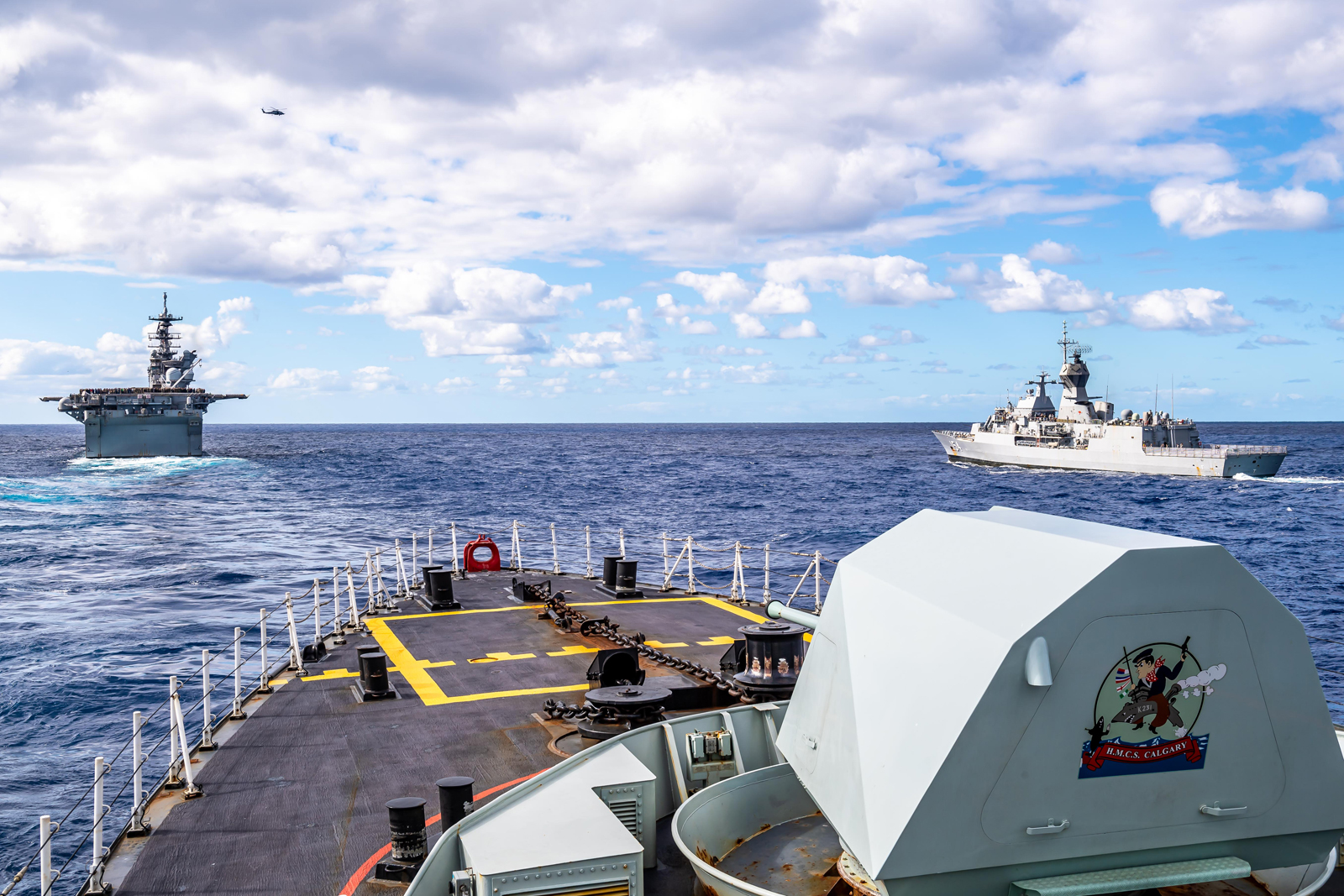 A view from HMCS Calgary of USS America, an amphibious assault ship and the lead of her class from the United States Navy, and HMAS Parramatta, an Anzac-class frigate from the Royal Australian Navy, as the ships maintain their position in formation with other ships in the Coral Sea  on July 22 during OPERATION Projection and Exercise Talisman Sabre 2021. Photos by Corporal Lynette Ai Dang, Canadian Armed Forces Photo