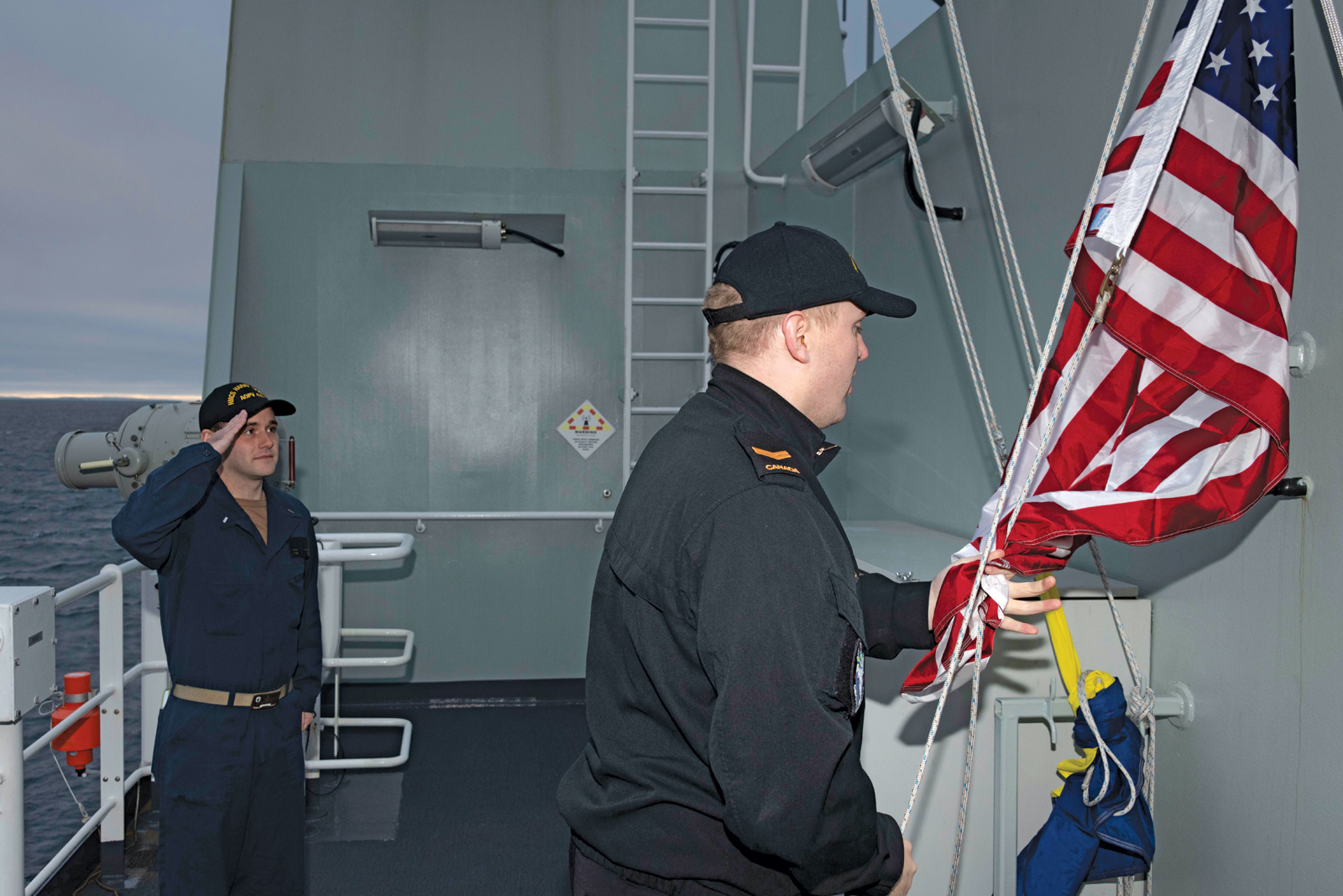 U.S. Navy sailor Lieutenant Junior Grade Kyle Luchau and an HMCS Harry DeWolf crewmember raise the United States flag in commemoration of 9/11. 